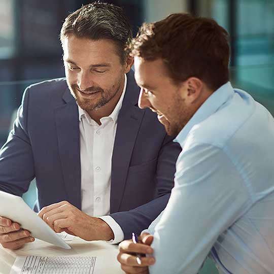Two happy business man looking at a tablet