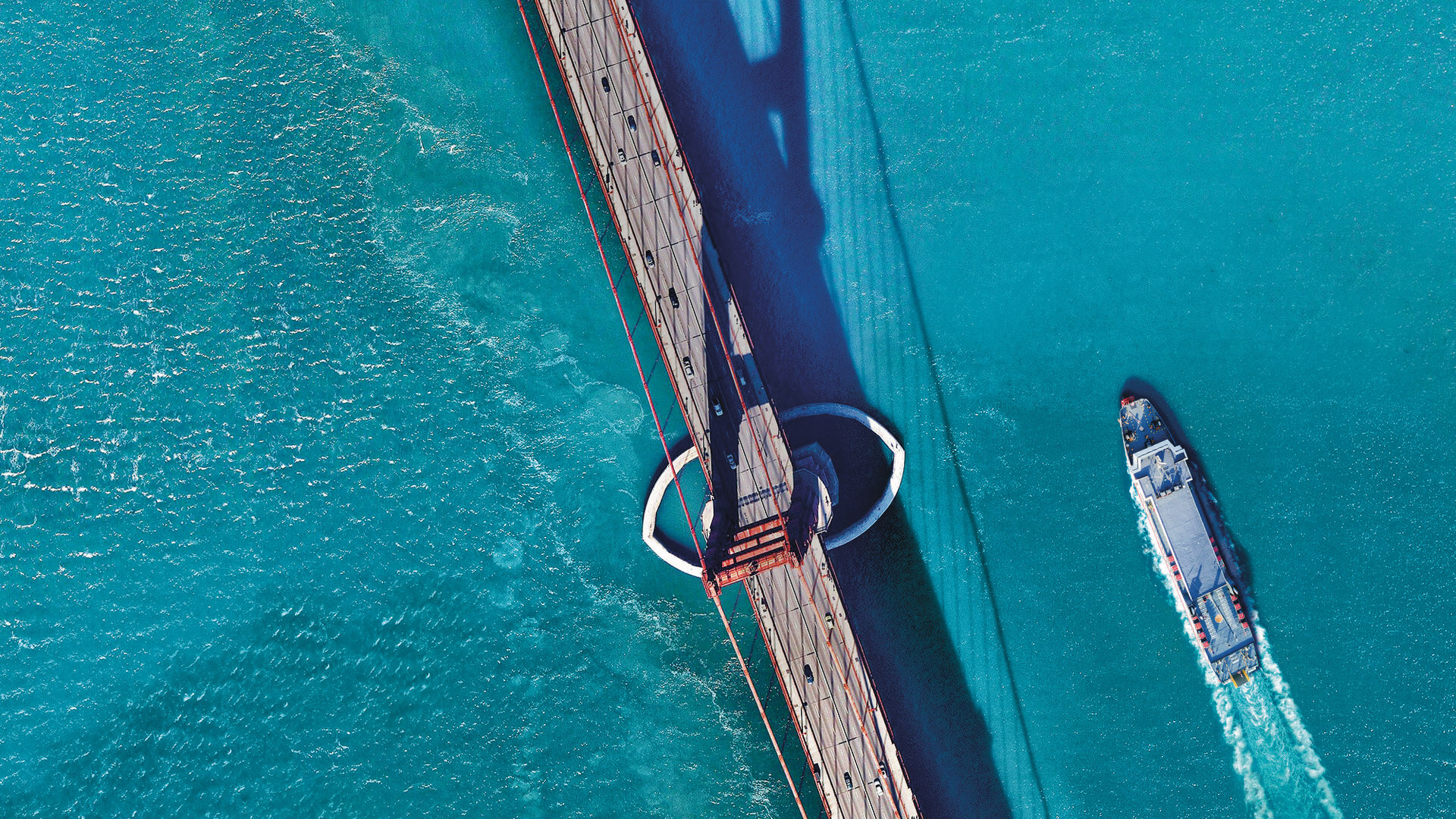 Aerial view of ship sailing alongside a bridge
