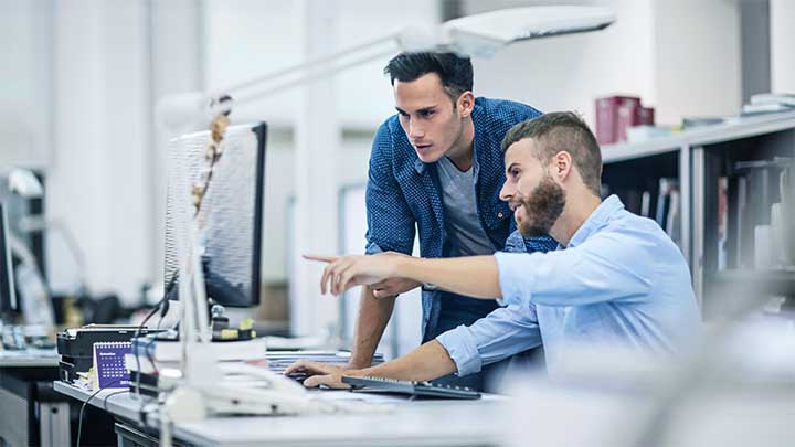 Two office workers looking at a screen