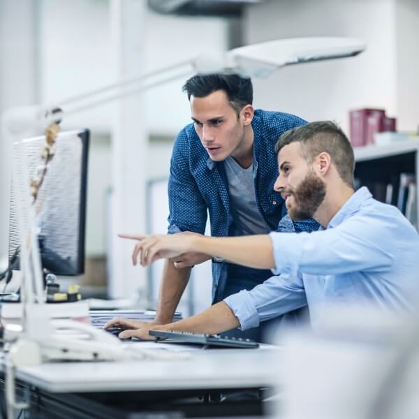 two office works in front of a computer screen