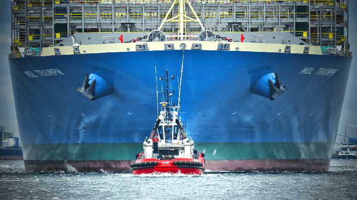 Tugboat in front of a large container ship