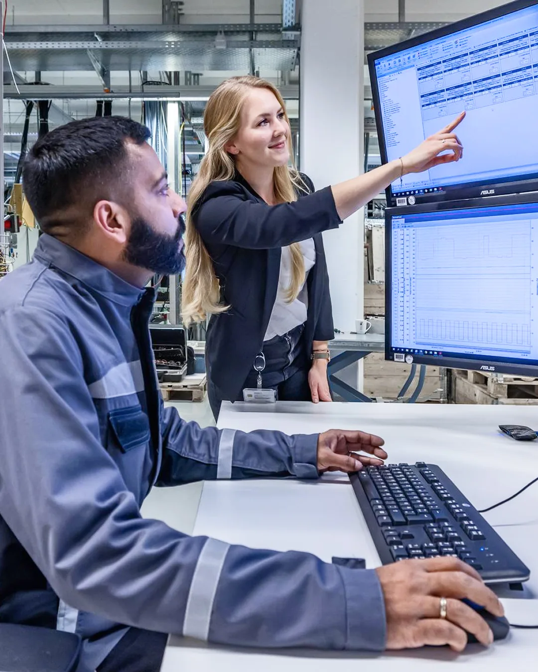 Engineer and technician analyzing engine performance data on computer screens.